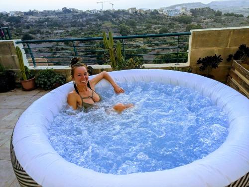 une femme dans un bain à remous sur un balcon dans l'établissement Paradise Gardens, à Ix-Xagħra