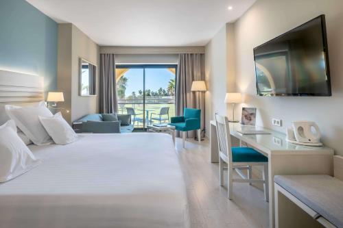 a hotel room with a large white bed and a desk at Barceló Costa Ballena Golf & Spa in Costa Ballena