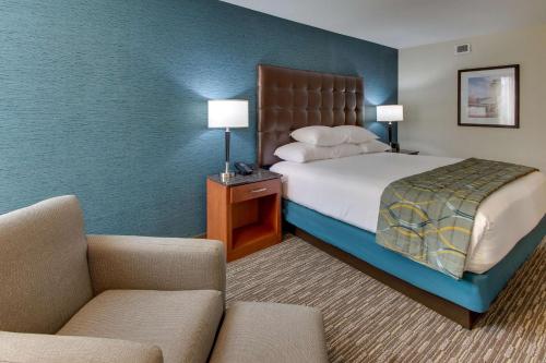 a hotel room with a bed and two chairs at Pear Tree Inn St. Louis Airport in Edmundson