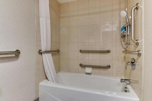 La salle de bains est pourvue d'une baignoire blanche et d'une douche. dans l'établissement Pear Tree Inn St. Louis Airport, à Edmundson