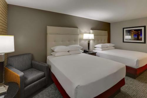 a hotel room with two beds and a chair at Drury Inn & Suites Columbus Dublin in Dublin