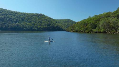 a person on a paddle board in a lake at rivescape holiday home at Berowra Waters in Berrilee