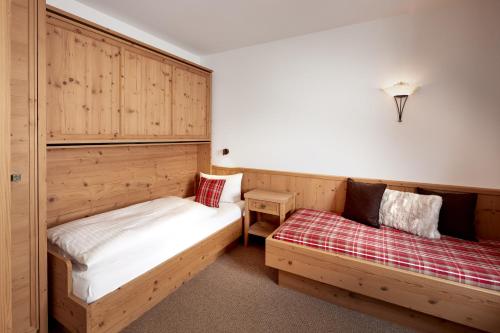 two beds in a room with wooden cabinets at Hotel Gletscherblick in Sankt Anton am Arlberg
