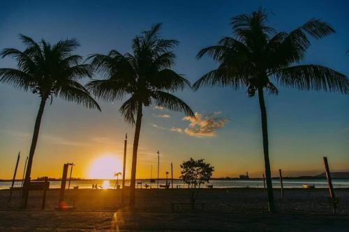 un grupo de palmeras en una playa al atardecer en Pousada dos Mestres, en Cabo Frío