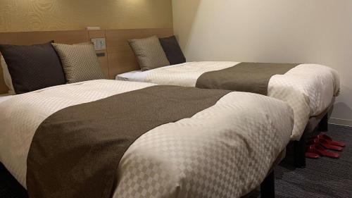 two beds in a hotel room with red shoes at The Celecton Kyoto Horikawa Sanjo in Kyoto