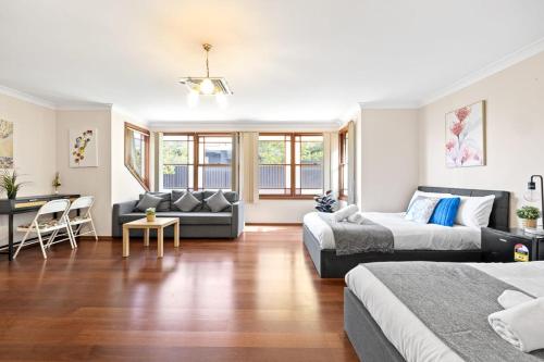 a living room with two beds and a couch at Quadruple Room w Ensuite in Gordon near Train & Bus in Pymble