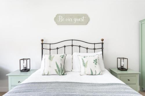 a bed with white pillows and a sign that says be can guest at Maldon Executive Apartments in Maldon