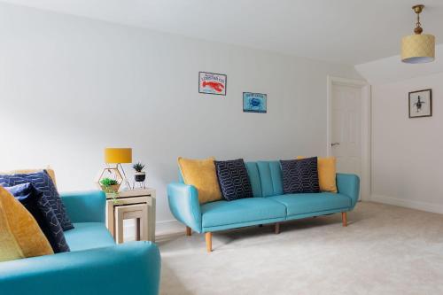 a living room with two blue couches and a table at Maldon Executive Apartments in Maldon