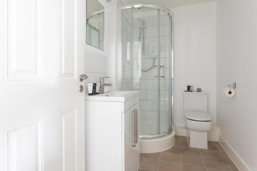 a white bathroom with a shower and a toilet at Maldon Executive Apartments in Maldon