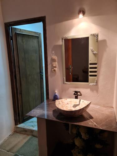 La salle de bains est pourvue d'un lavabo en pierre et d'un miroir. dans l'établissement Hôtel et Restaurant ARIJ, à Midelt