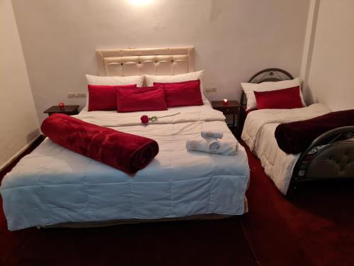 a bedroom with two beds with red pillows at Hôtel et Restaurant ARIJ in Midelt