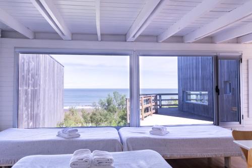 Dos camas en una habitación con vista al mar. en Departamento frente al mar Sauce Grande REFUGIOS DEL SAUCE, en Monte Hermoso