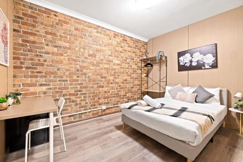 a bedroom with a brick wall and a bed at Double Room in Gordon near Train & Bus - 1 person in Pymble
