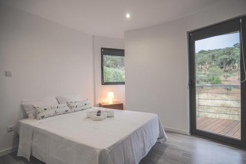 a white bedroom with a bed with a large window at Bela Vista Silo Housing in Alfândega da Fé