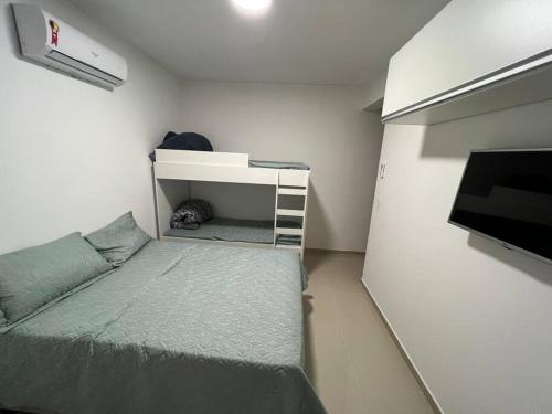 a small bedroom with a bed and a tv at Apartamento encantador próximo a Praia Brava in Matinhos