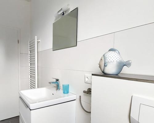 ein weißes Badezimmer mit einem Waschbecken und einem Spiegel in der Unterkunft Hangar 19 Wohnung Seerose 2-3 in Schwerin