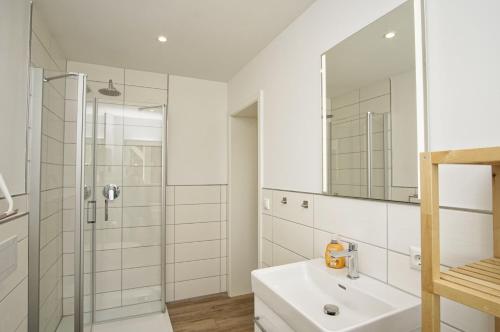 a white bathroom with a sink and a shower at Ruhig und idyllische Lage, strandnah, gratis Nutzung vom AHOI Erlebnisbad und Sauna in Sellin - Gutshaus Silvitz FeWo 02 in Bergen auf Rügen