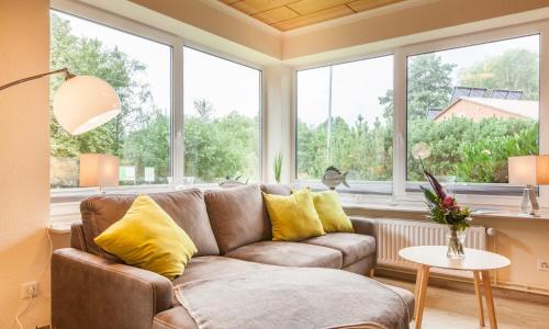 a living room with a couch and large windows at an Diek" mit Wallbox in Ekenis