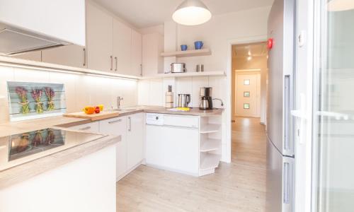 a white kitchen with white cabinets and white appliances at an Diek" mit Wallbox in Ekenis