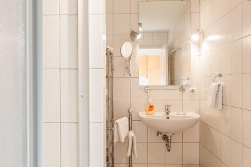 Un baño blanco con lavabo y espejo. en Ellerüher Weg Maisonette, en Kappeln