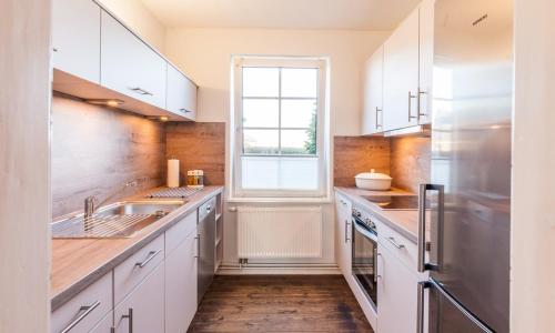 a kitchen with white cabinets and a window at Falshöft 1a in Nieby