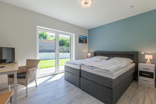 ein Schlafzimmer mit einem Bett, einem Schreibtisch und einem Fernseher in der Unterkunft Moin Moin in Nieby