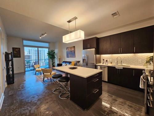 a kitchen with a kitchen island and a living room at Luxury Highrise in Midtown - Skyline Views and Chic Decor in Houston
