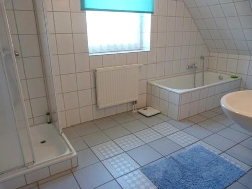a white bathroom with a tub and a sink at Schmiedekoppel in Kronsgaard