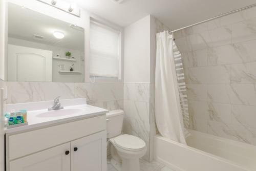 y baño blanco con lavabo, aseo y bañera. en Modern one bedroom apartment, en Elizabeth