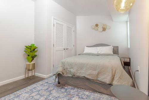 a white bedroom with a bed and a plant at Modern one bedroom apartment in Elizabeth