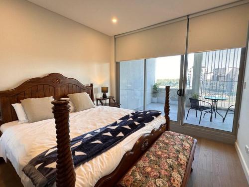 a bedroom with a large bed and a balcony at Olympic park&Luxury 2b2b1p Apt pool& Free parking in Sydney