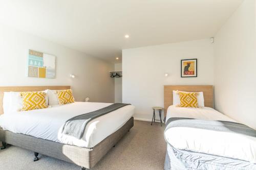 two beds in a room with white walls at Lakeside Escape in Queenstown