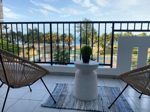 a balcony with two chairs and a potted plant at Luquillo Beach & Ocean Fresh in Luquillo