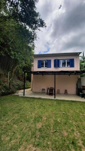 uma casa branca com janelas azuis e um quintal em Casa Palácio de Cristal no centro Histórico de Petrópolis em Petrópolis