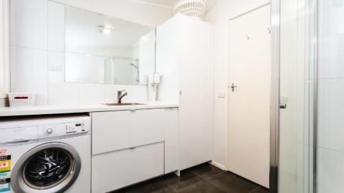 uma lavandaria branca com máquina de lavar e secar roupa em The Grove em Flinders