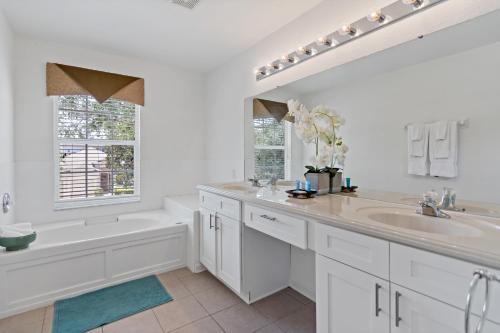 a white bathroom with a tub and a sink and a bath tubermott at The Pink House at Windsor Hills in Orlando