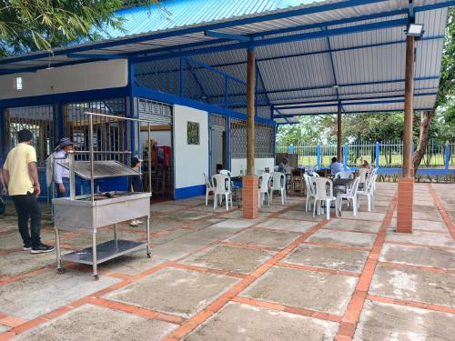 a man standing in front of a building with tables and chairs at Hotel campestre la Maria in Villavicencio