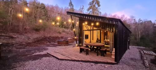 Cabaña pequeña con terraza de madera y mesa en Cabaña en el bosque-Termas de Chillán, en Recinto