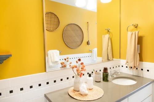 Baño amarillo con lavabo y espejo en Sleepover No 103 en Filadelfia