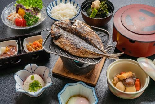 un tavolo sormontato da un pesce e ciotole di cibo di Atagawakan a Higashiizu