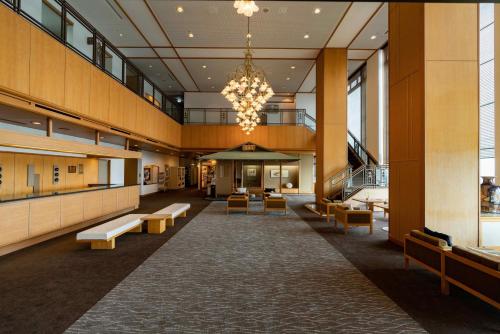 a lobby of a building with benches and a chandelier at Atagawakan in Higashiizu