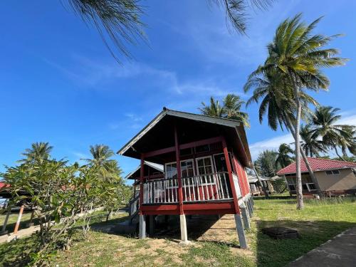 ein kleines Haus mit einem Balkon neben einer Palme in der Unterkunft PCB BEACH RESORT in Kota Bharu