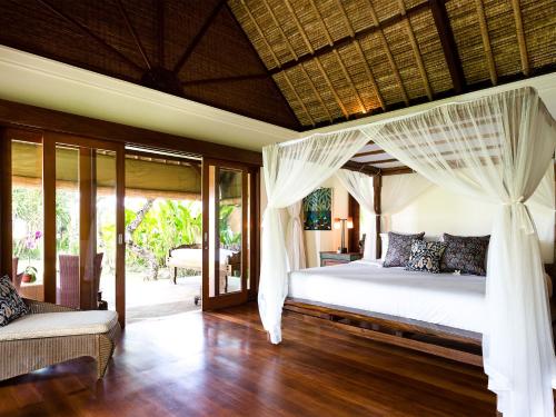 - une chambre dotée d'un lit avec des rideaux blancs dans l'établissement Villa Maridadi by Elite Havens, à Canggu