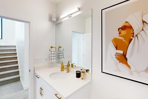 uma casa de banho com um lavatório e uma foto emoldurada de uma mulher em Modern Peaks Townhome em Denver