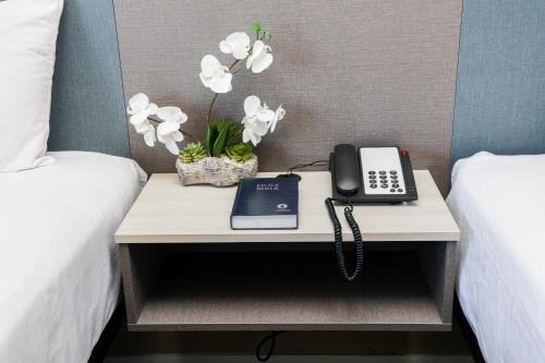 a phone on a table between two beds at Sea Breeze Inn - San Simeon in San Simeon