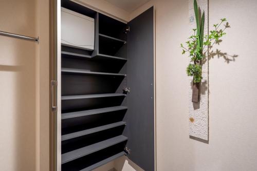 a walk in closet with black shelves and a plant at RESI STAY Mayu Grace Hotel in Kyoto