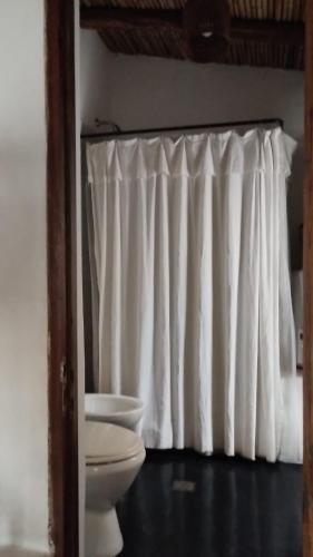 a bathroom with a toilet and a white curtain at La Calabaza Cabaña in Tilcara