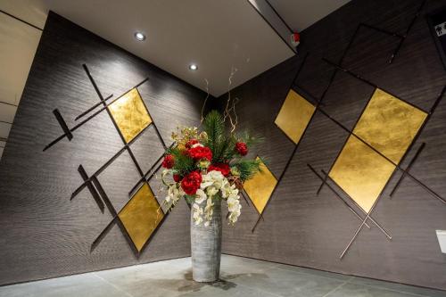 a vase with flowers in front of a wall at RESI STAY Mayu Grace Hotel in Kyoto