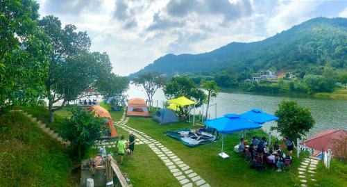 un gruppo di persone seduti sotto gli ombrelloni vicino a un lago di Nhà trên cây a Hanoi