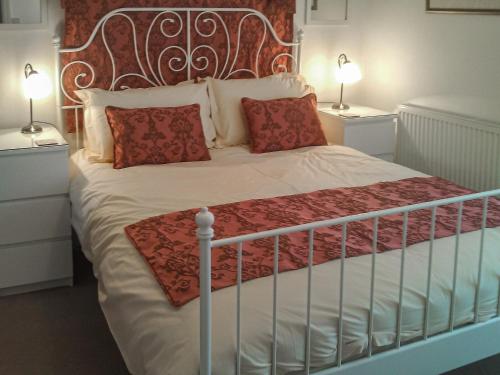 a bedroom with a large bed with red pillows at Squirrel Cottage in Windermere